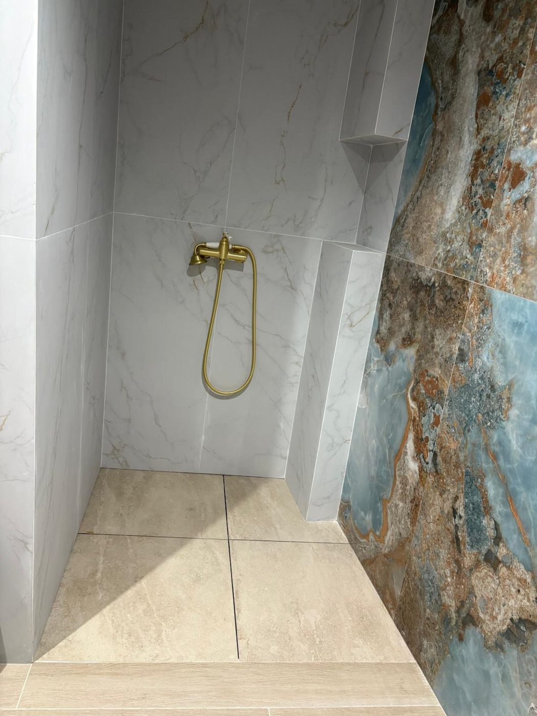 Ducha con grifería dorada y porcelánico en Córdoba