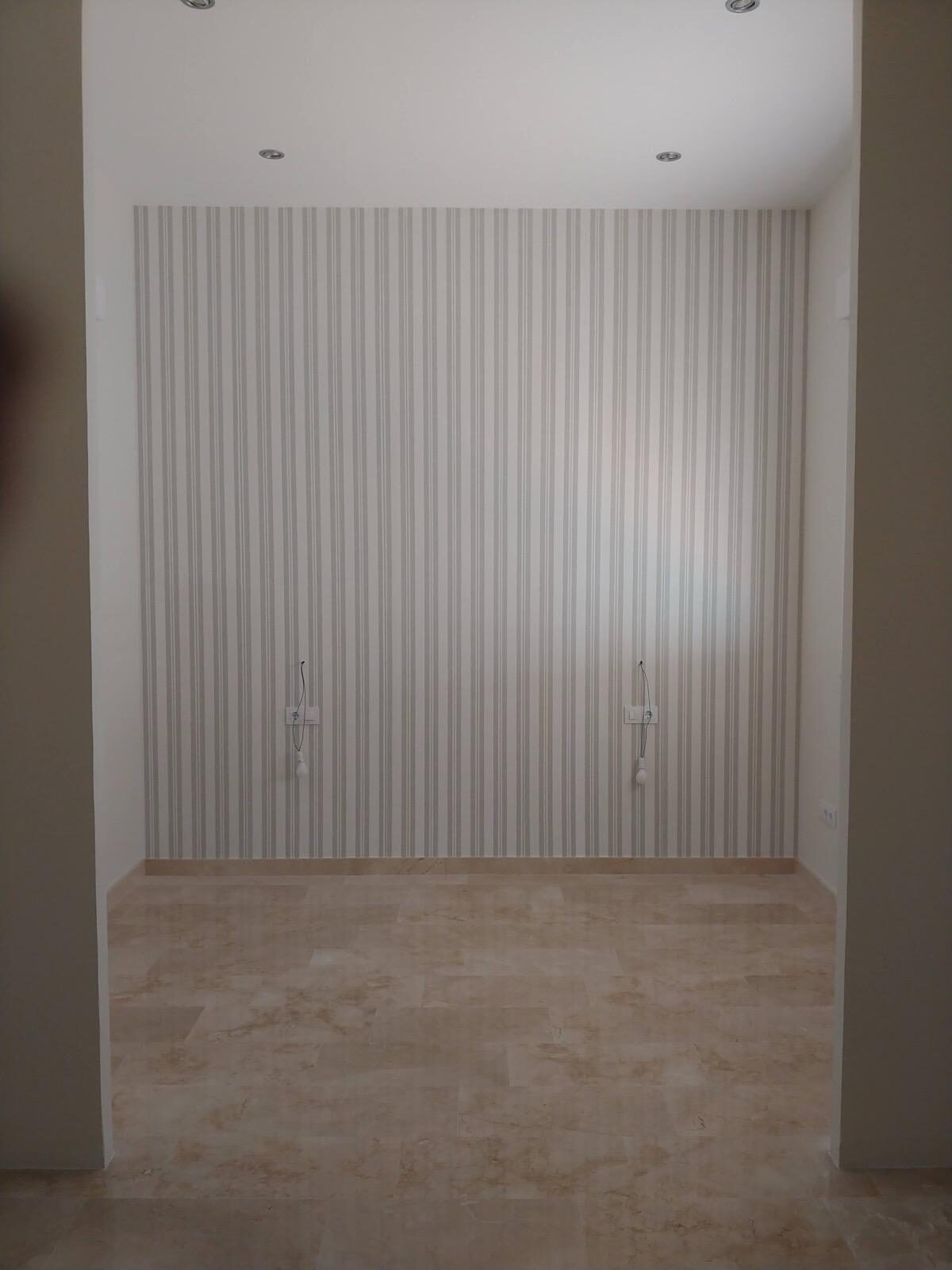 Habitación con papel pintado de rayas tras reforma integral en Córdoba