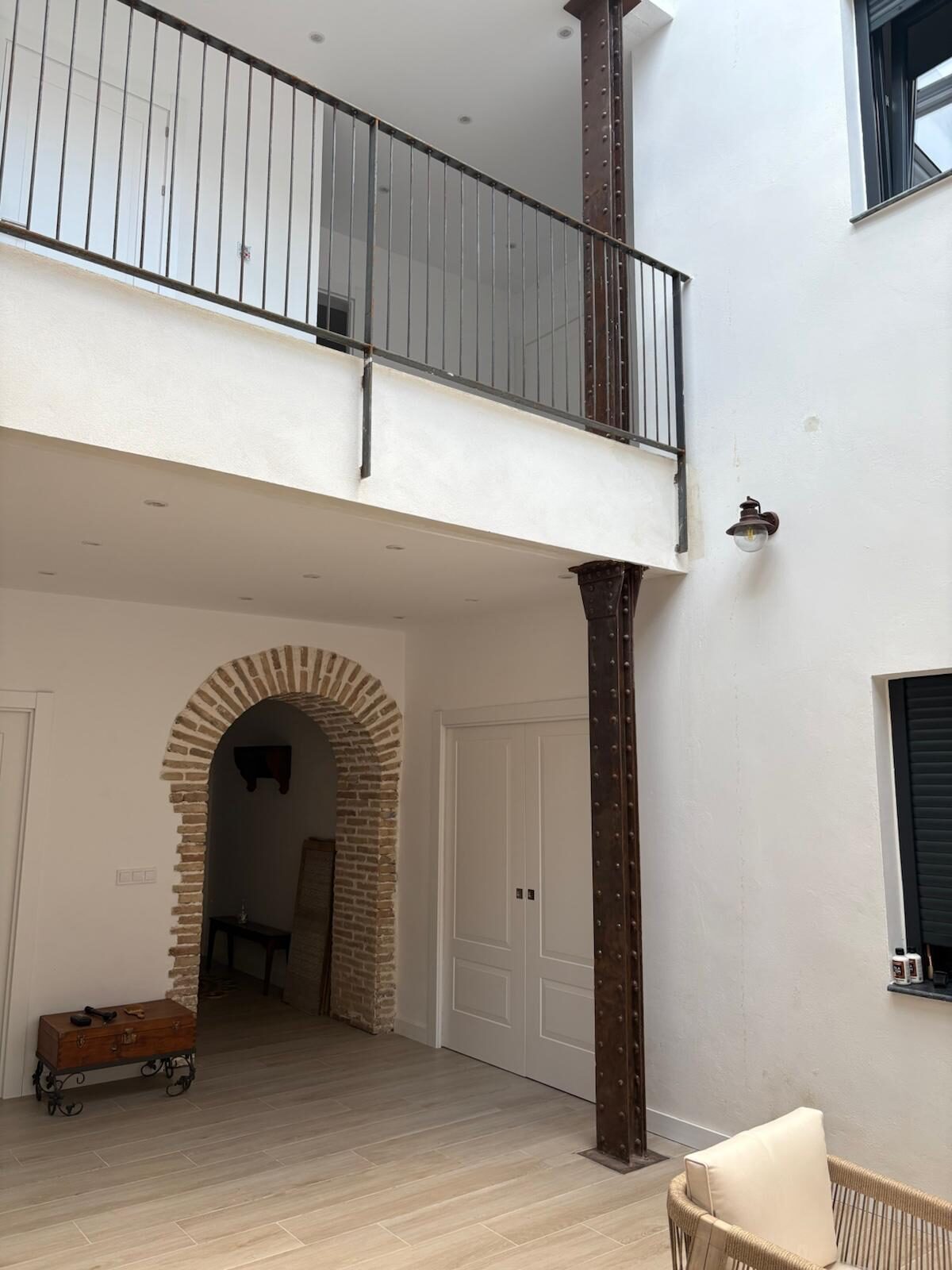 Salón con arco de ladrillo visto y columna de hierro en reforma de vivienda histórica en Córdoba